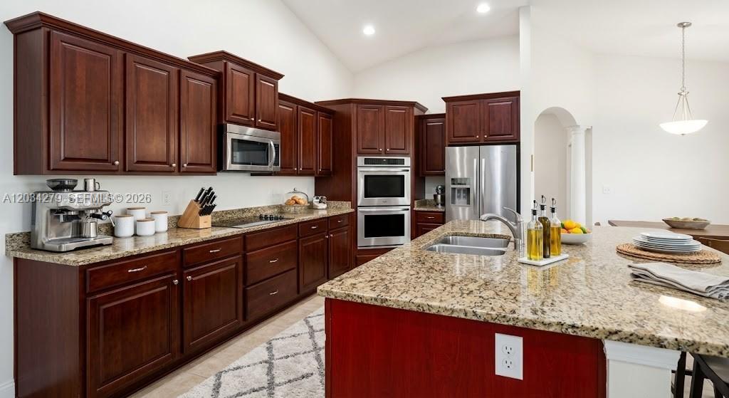A kitchen features dark wood cabinetry, granite countertops, stainless steel appliances, and a central island — 10255 Guatemala St, Cooper City FL 33026, COOPER CITY, FL