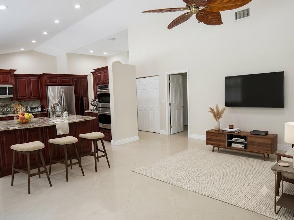 A kitchen with dark wood cabinets and an island opens into a living area — 10255 Guatemala St, Cooper City FL 33026, COOPER CITY, FL