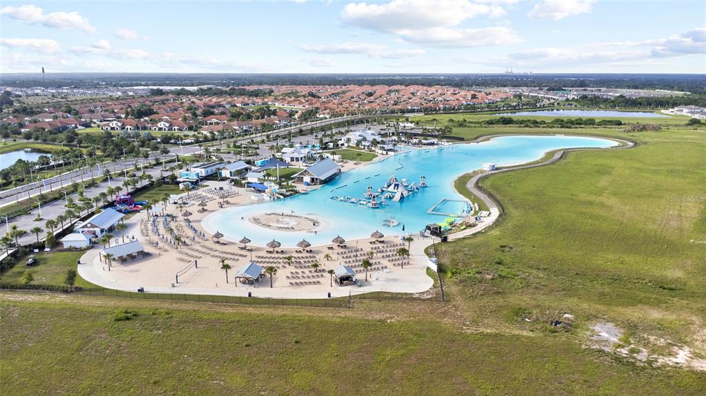 An aerial view shows a large man-made lagoon with a sandy beach and surrounding buildings — 5025 JACKEL CHASE DRIVE, WIMAUMA, FL