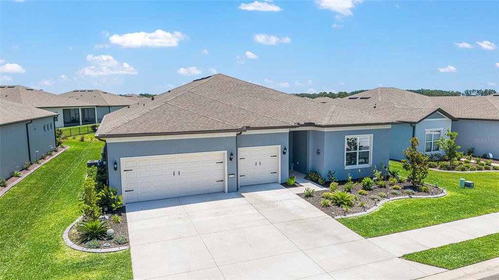 An aerial view of a blue single-story house with a three-car garage and landscaping — 6046 SW 86 CIRCLE, OCALA, FL