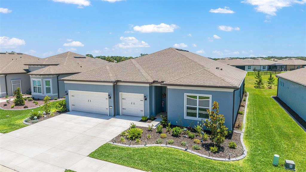 An aerial view of a blue single-story house with a two-car garage and landscaping — 6046 SW 86 CIRCLE, OCALA, FL