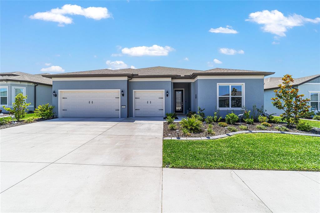 A single-story blue house with a three-car garage and a landscaped front yard — 6046 SW 86 CIRCLE, OCALA, FL