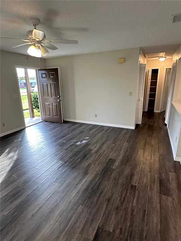 A living room features dark wood-look flooring, a ceiling fan, and an open entryway — 111 LOUISIANA AVENUE, ST CLOUD, FL