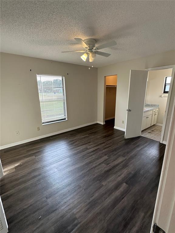 A bedroom features dark wood-look flooring, a ceiling fan, a window, and an attached bathroom — 111 LOUISIANA AVENUE, ST CLOUD, FL