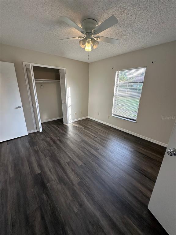 An empty bedroom features dark wood-look flooring, a ceiling fan, and a white closet — 111 LOUISIANA AVENUE, ST CLOUD, FL