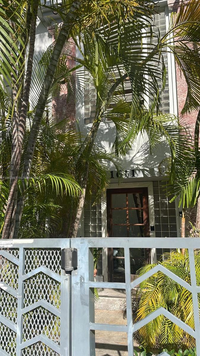 A gated entrance leads to a house exterior with glass block windows and palm trees — 1611 Euclid Ave # 3, Miami Beach FL 33139, MIAMI BEACH, FL
