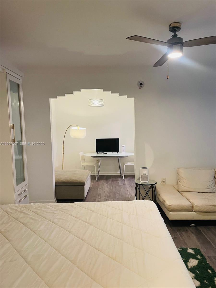 A bedroom with a white bed, a sofa, and an arched entryway to a dining area — 1611 Euclid Ave # 3, Miami Beach FL 33139, MIAMI BEACH, FL