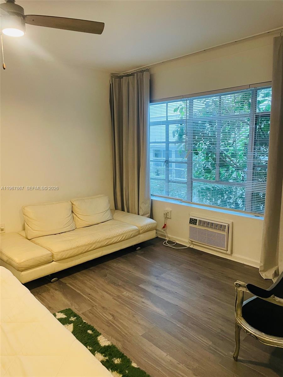 A room features a white sofa, wood-look flooring, a window with blinds, and an air conditioner — 1611 Euclid Ave # 3, Miami Beach FL 33139, MIAMI BEACH, FL