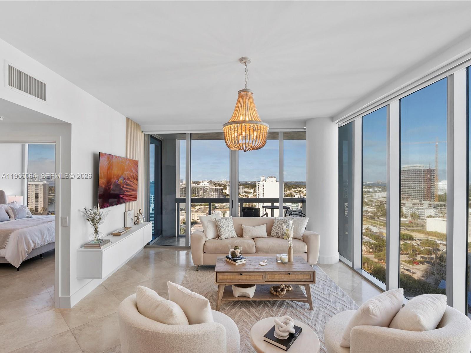A modern living room features a beige sofa, two armchairs, and floor-to-ceiling windows with views — 6899 Collins Ave # 1704, Miami Beach FL 33141, MIAMI BEACH, FL