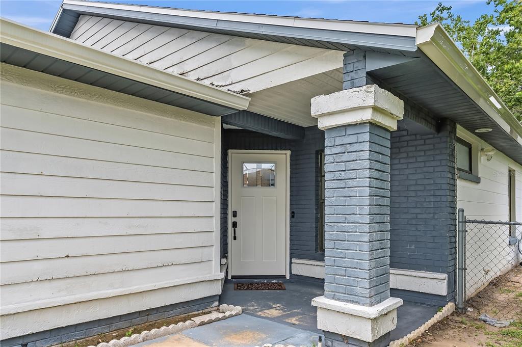 The front entrance of a house features a white door, gray brick, and white siding — 182 PINEWOOD CIRCLE, KISSIMMEE, FL
