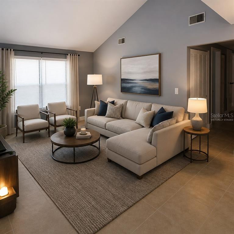 This virtually staged living room features a sectional sofa, two armchairs, and a vaulted ceiling — 1019 PENINSULA ROAD, TARPON SPRINGS, FL