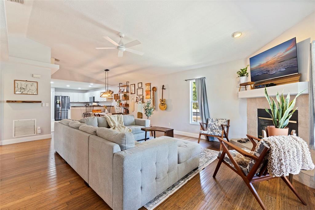 A living room with a sectional sofa, fireplace, and hardwood floors opens to a kitchen — 2462 14TH AVENUE N, ST PETERSBURG, FL