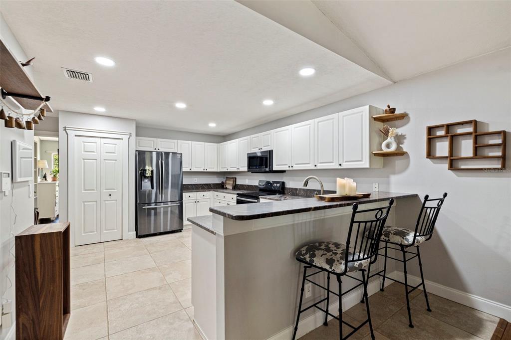 A kitchen with white cabinets, stainless steel appliances, a breakfast bar, and tile flooring — 2462 14TH AVENUE N, ST PETERSBURG, FL