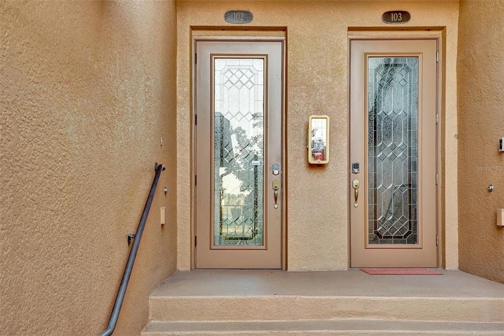 Two adjacent exterior doors with glass inserts and unit numbers 102 and 103 — 6911 GRAND ESTUARY TRAIL UNIT 102, BRADENTON, FL
