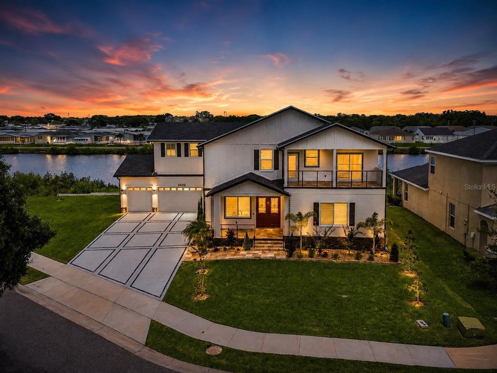 An aerial view of a two-story house with a driveway and a waterfront backyard at sunset — 3426 CHANNELSIDE COURT, SAFETY HARBOR, FL