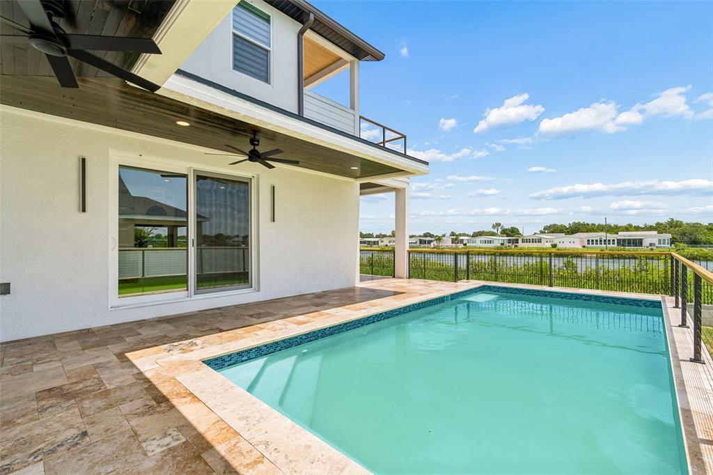 A backyard features a swimming pool, a tiled patio, and a covered porch with ceiling fans — 3426 CHANNELSIDE COURT, SAFETY HARBOR, FL