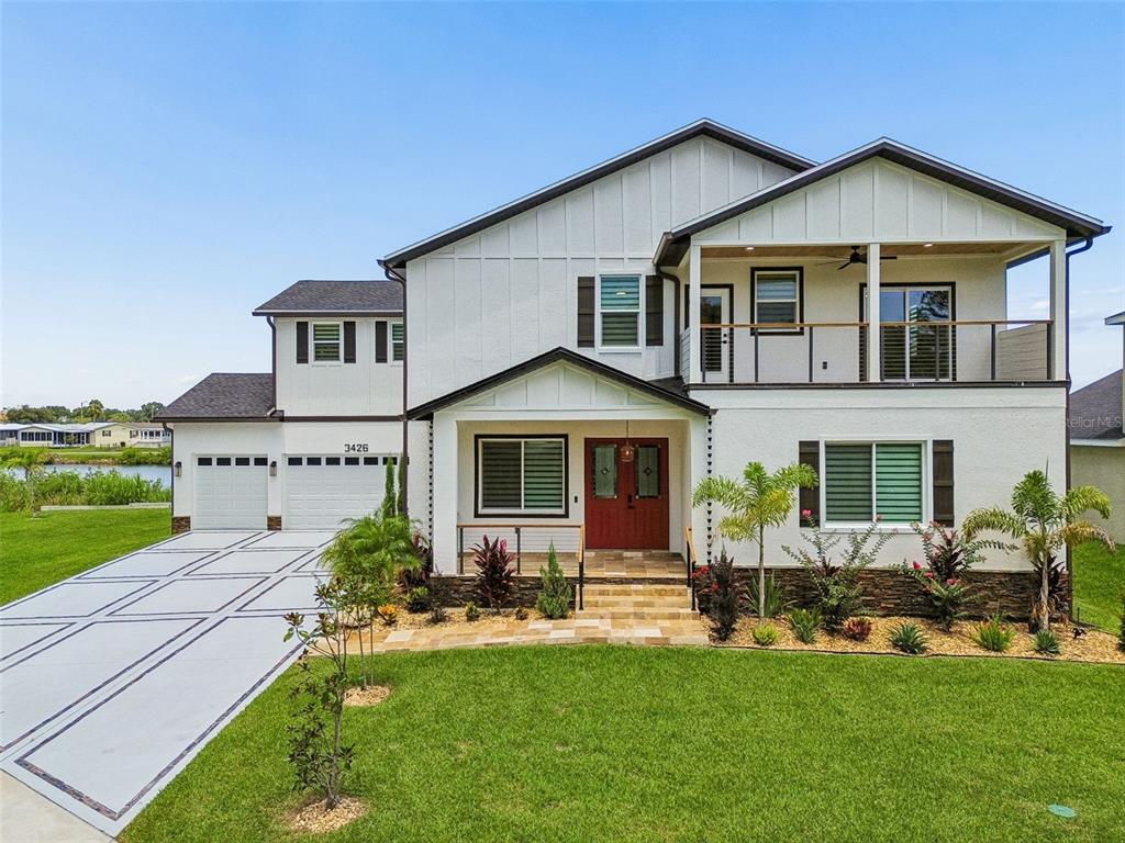 A two-story white house with a garage, balcony, and a paved driveway sits on grass — 3426 CHANNELSIDE COURT, SAFETY HARBOR, FL