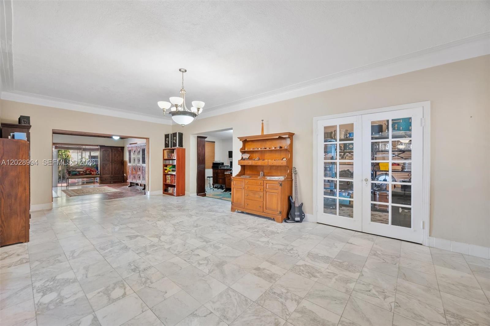 A spacious room features marble tile flooring, a chandelier, and white French doors — 1727 SW 11th Ter, Miami FL 33135, MIAMI, FL
