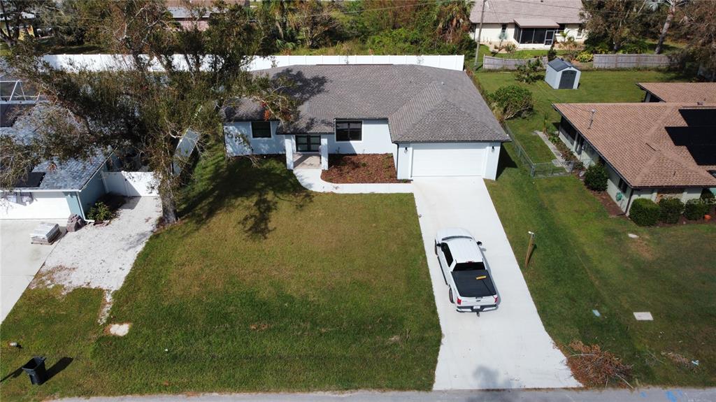 An aerial view shows a single-story house with a white exterior, gray roof, and driveway — 20296 RUTHERFORD AVENUE, PORT CHARLOTTE, FL