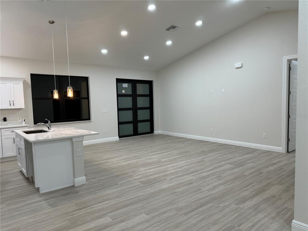 A modern open-concept kitchen and living area features light wood-look flooring and recessed lighting — 20296 RUTHERFORD AVENUE, PORT CHARLOTTE, FL