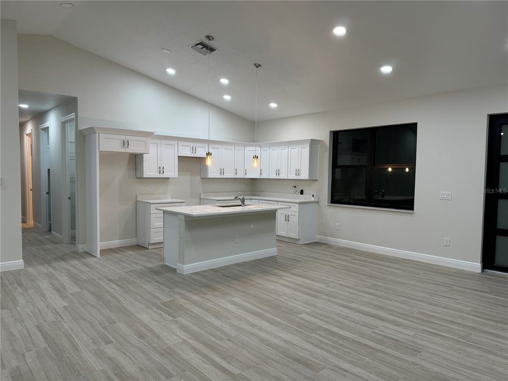 A kitchen with white cabinets, a central island, and light wood-look flooring — 20296 RUTHERFORD AVENUE, PORT CHARLOTTE, FL