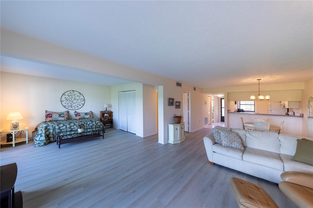 A spacious living area features light wood-look flooring, a daybed, and an adjacent dining space — 696 BIRD BAY DRIVE W UNIT 138, VENICE, FL