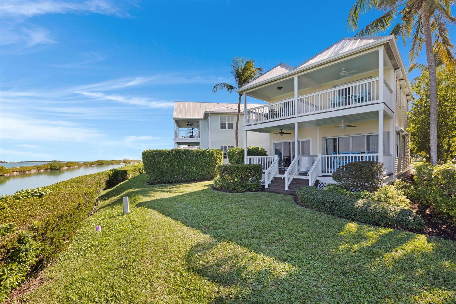 A two-story house with balconies overlooks a grassy lawn and a body of water — 2002 Marina Villa Drive, FL 33050, FL