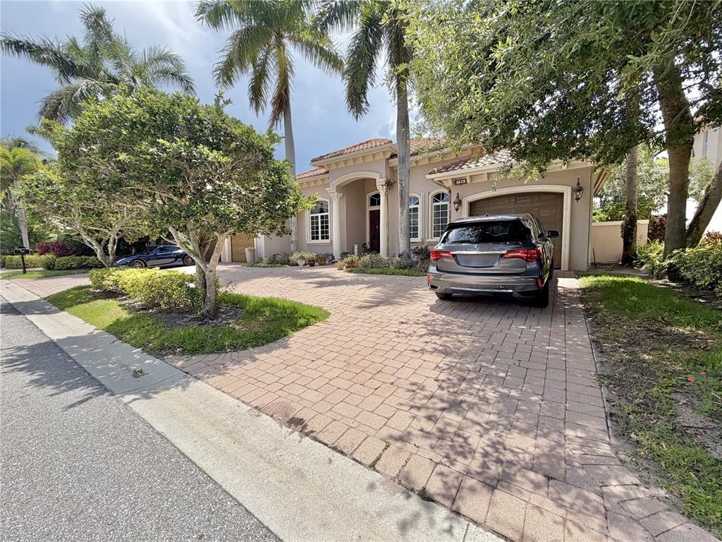A single-story house with a paved driveway, a two-car garage, and palm trees in front — 785 HARBOUR ISLE PLACE, NORTH PALM BEACH, FL