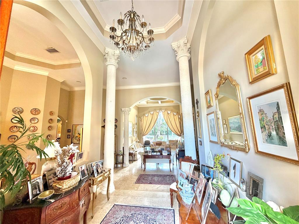 A grand foyer features marble floors, decorative columns, a crystal chandelier, and arched entryways — 785 HARBOUR ISLE PLACE, NORTH PALM BEACH, FL