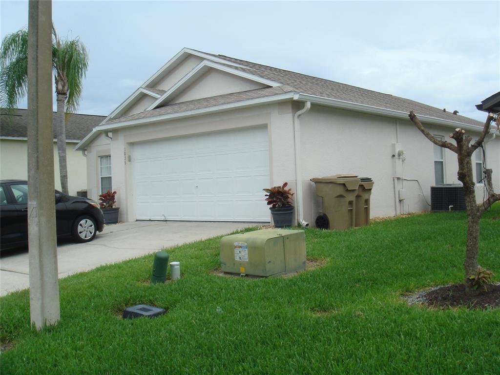 A light-colored house with a two-car garage, a driveway, and a green lawn — 1036 CLEAR CREEK CIRCLE, CLERMONT, FL
