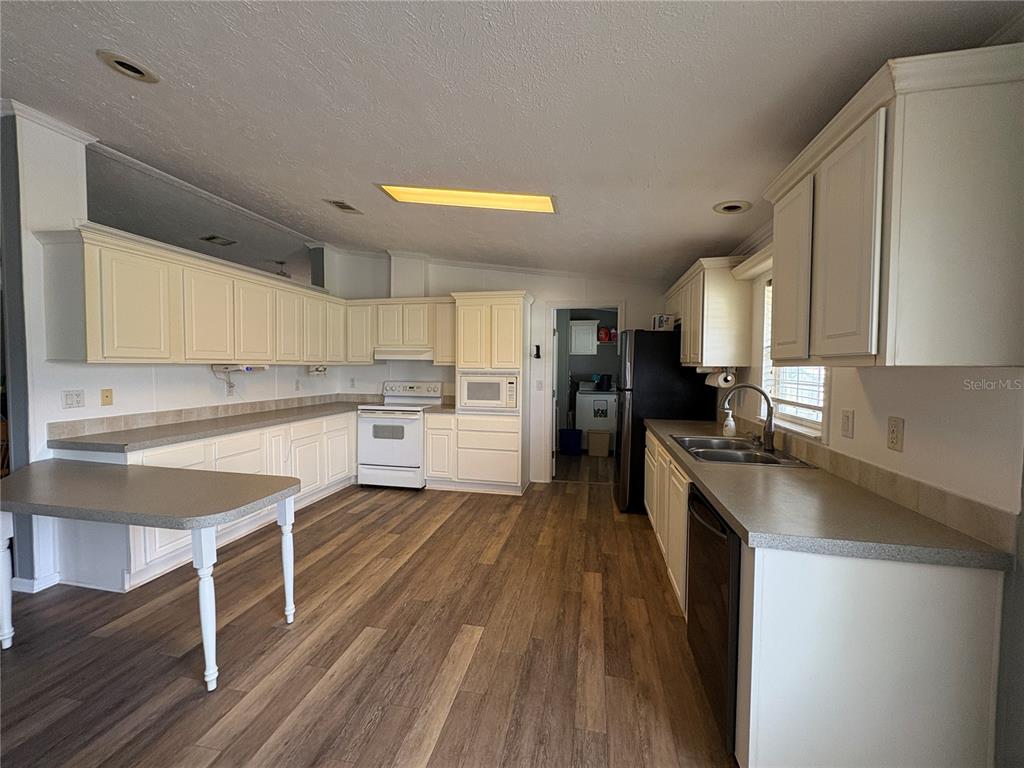 A kitchen features white cabinets, laminate countertops, a white stove, and wood-look flooring — 9145 LINCOLN ROAD, ST CLOUD, FL