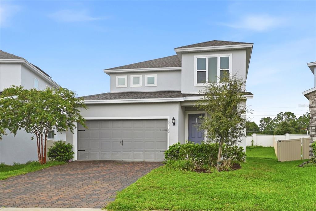 A two-story house with a gray garage, a paved driveway, and a small front yard — 4386 DAVOS DRIVE, CLERMONT, FL