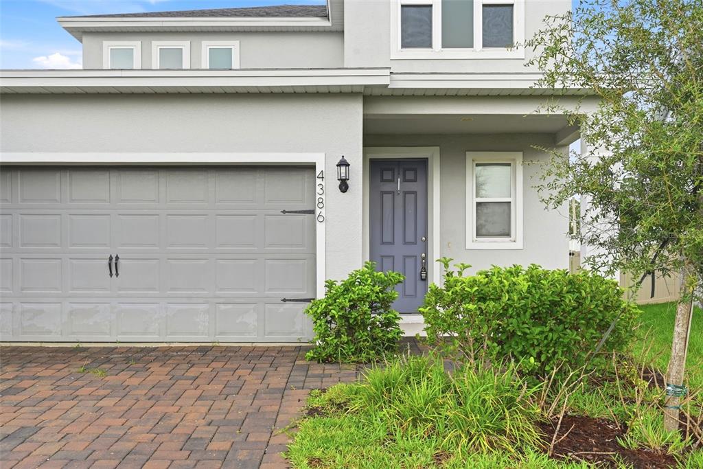 A gray house exterior features a two-car garage, a blue front door, and landscaping — 4386 DAVOS DRIVE, CLERMONT, FL