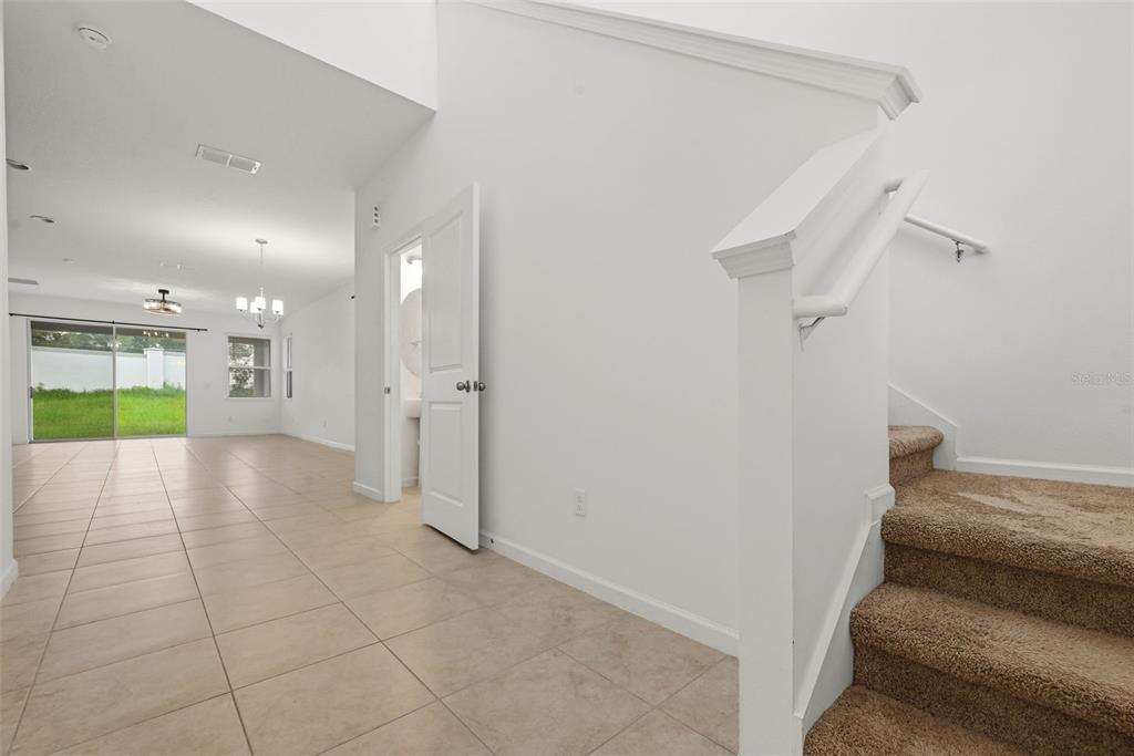 A tiled entryway leads to an open living area with a staircase and a bathroom — 4386 DAVOS DRIVE, CLERMONT, FL