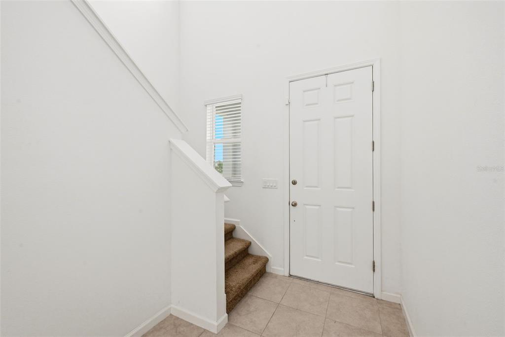 A white entry foyer features tile flooring, a carpeted staircase, and a white front door — 4386 DAVOS DRIVE, CLERMONT, FL