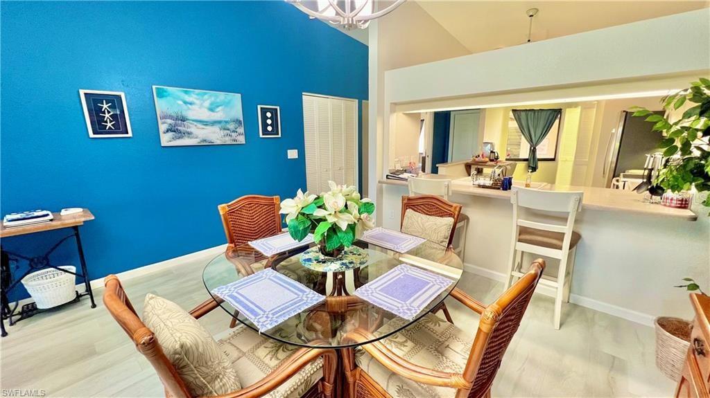 A dining area features a glass-topped table, wicker chairs, and a vibrant blue accent wall — 1640 ATARES DRIVE UNIT 31, PUNTA GORDA, FL