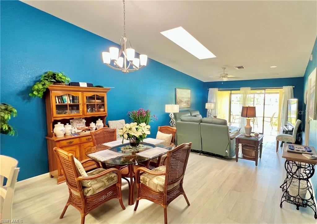 A dining area with a glass table and wicker chairs sits before a blue wall — 1640 ATARES DRIVE UNIT 31, PUNTA GORDA, FL