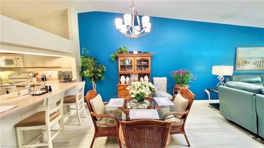 A dining area with a glass table, wicker chairs, and a blue accent wall — 1640 ATARES DRIVE UNIT 31, PUNTA GORDA, FL