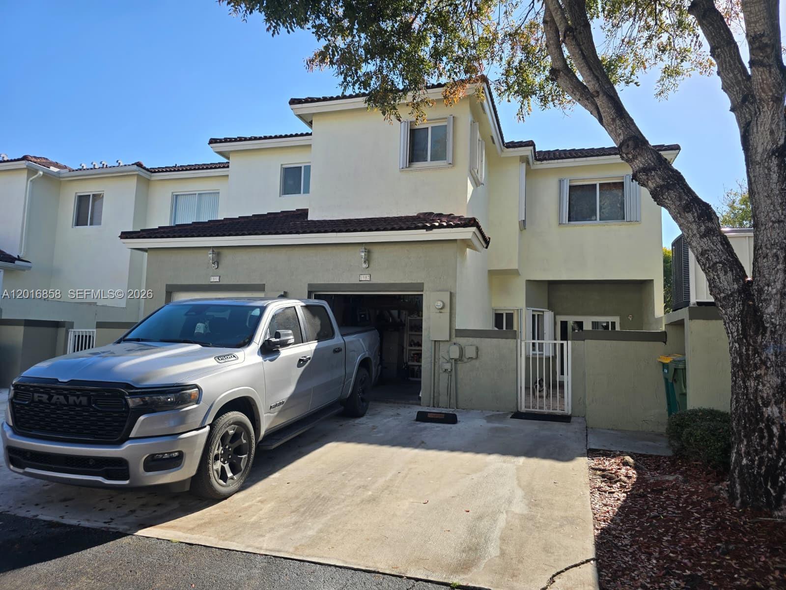 A silver pickup truck is parked in the driveway of a two-story suburban townhouse — 1987 SE 23rd Rd, Homestead FL 33035, HOMESTEAD, FL