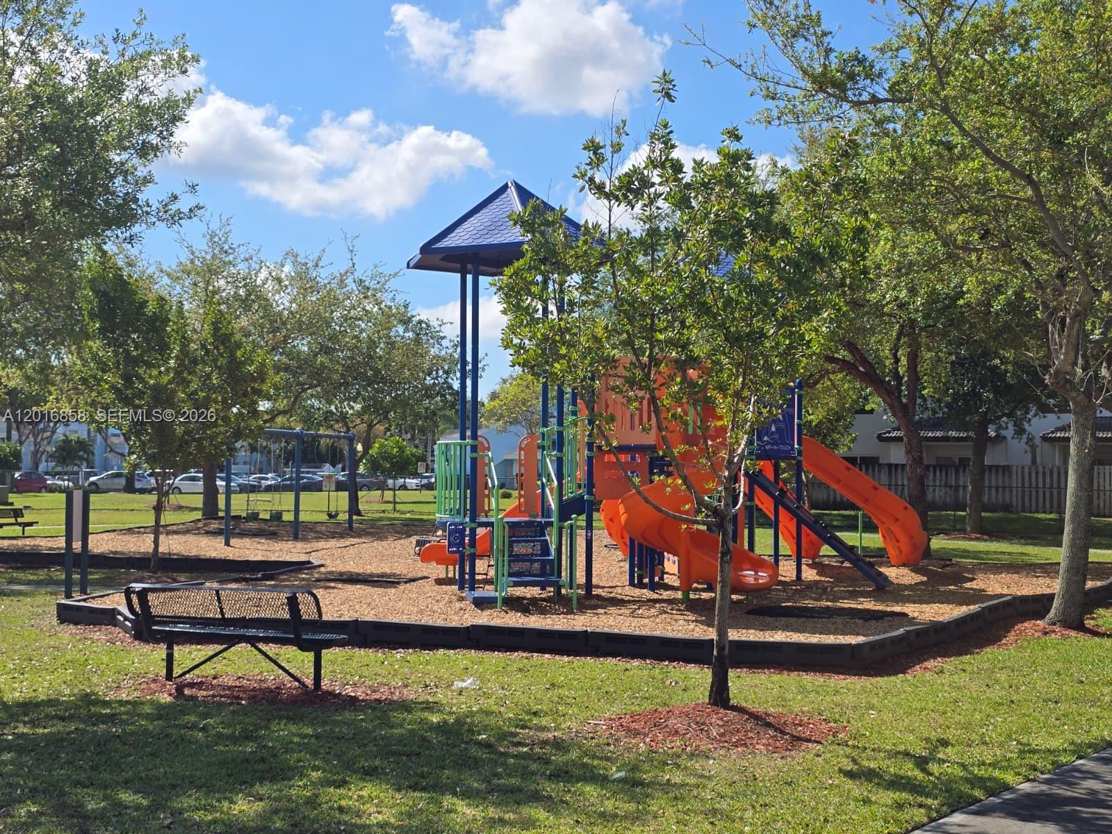 A playground with a multi-level orange slide structure, a metal bench, and surrounding trees — 1987 SE 23rd Rd, Homestead FL 33035, HOMESTEAD, FL