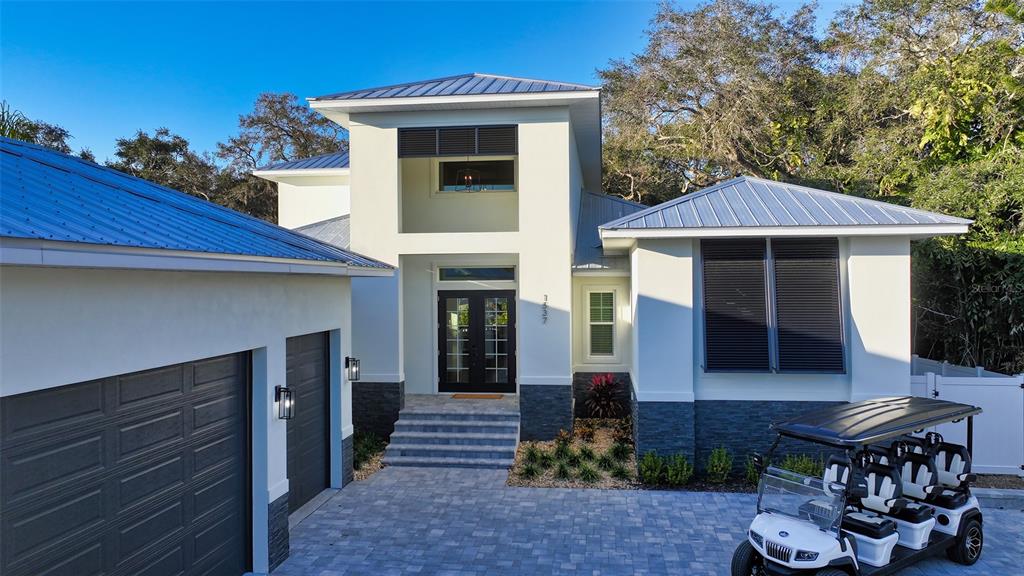 A modern white house with a metal roof, dark garage doors, and a golf cart parked — 1537 SIESTA DRIVE, SARASOTA, FL