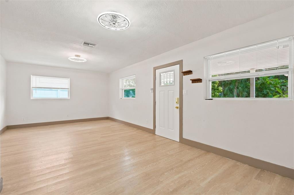An empty room with white walls, light wood-look flooring, a white door, and two windows — 6691 56TH AVENUE N, ST PETERSBURG, FL
