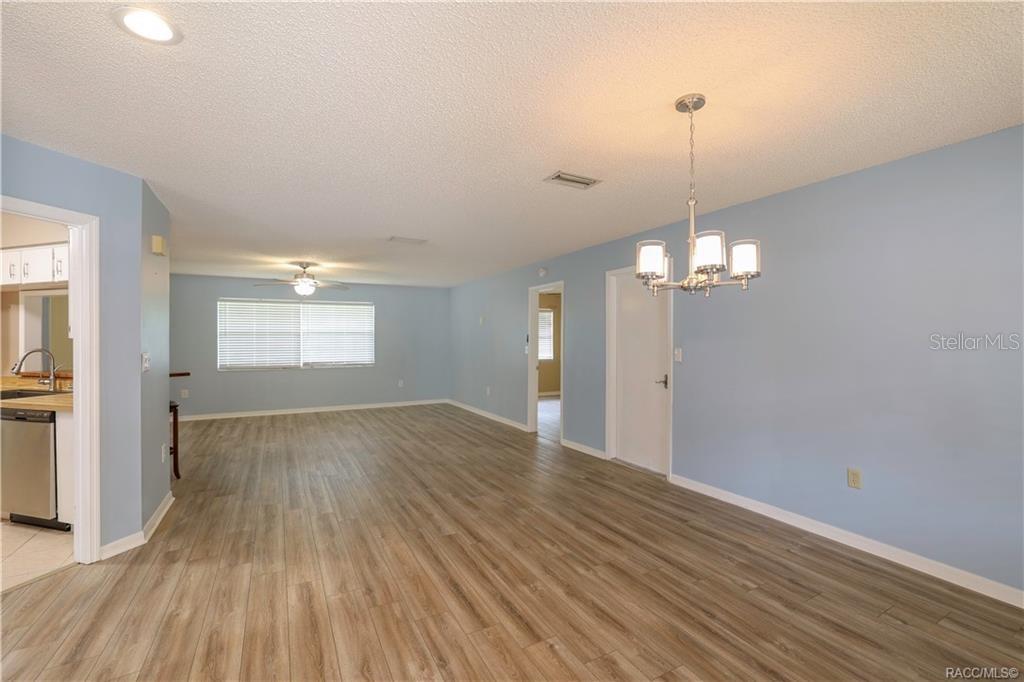 A light blue dining room features wood-look flooring and a hanging chandelier — 3637 N LAURELWOOD LOOP, BEVERLY HILLS, FL