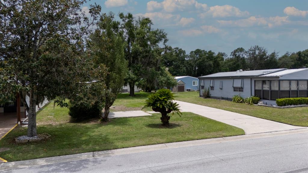 A gray manufactured home sits on a lot with a concrete driveway and mature trees — 35100 COLONY HILLS DRIVE, ZEPHYRHILLS, FL