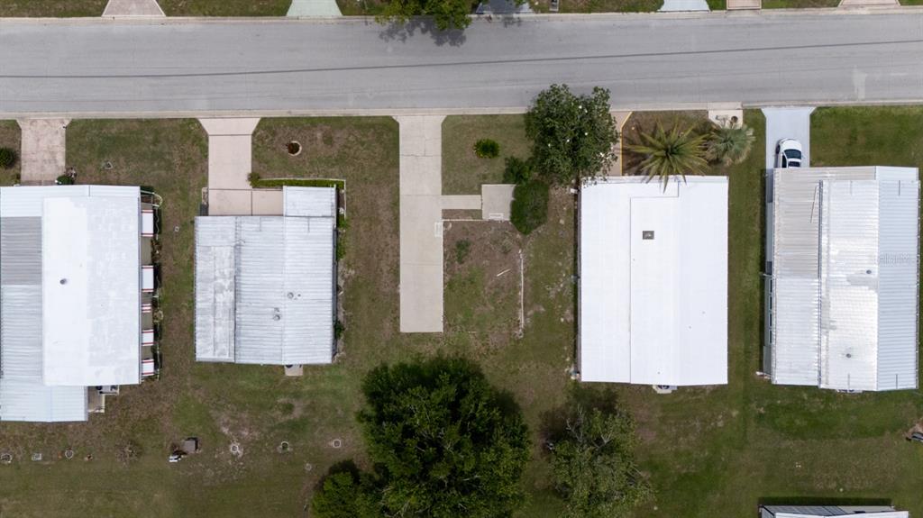 An aerial view shows four mobile homes with metal roofs and driveways along a street — 35100 COLONY HILLS DRIVE, ZEPHYRHILLS, FL