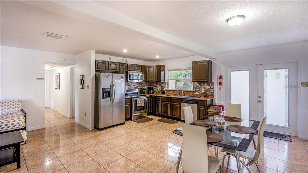 A kitchen and dining area features dark wood cabinets, stainless steel appliances, and tile flooring — 2721 RAEFORD ROAD, ORLANDO, FL