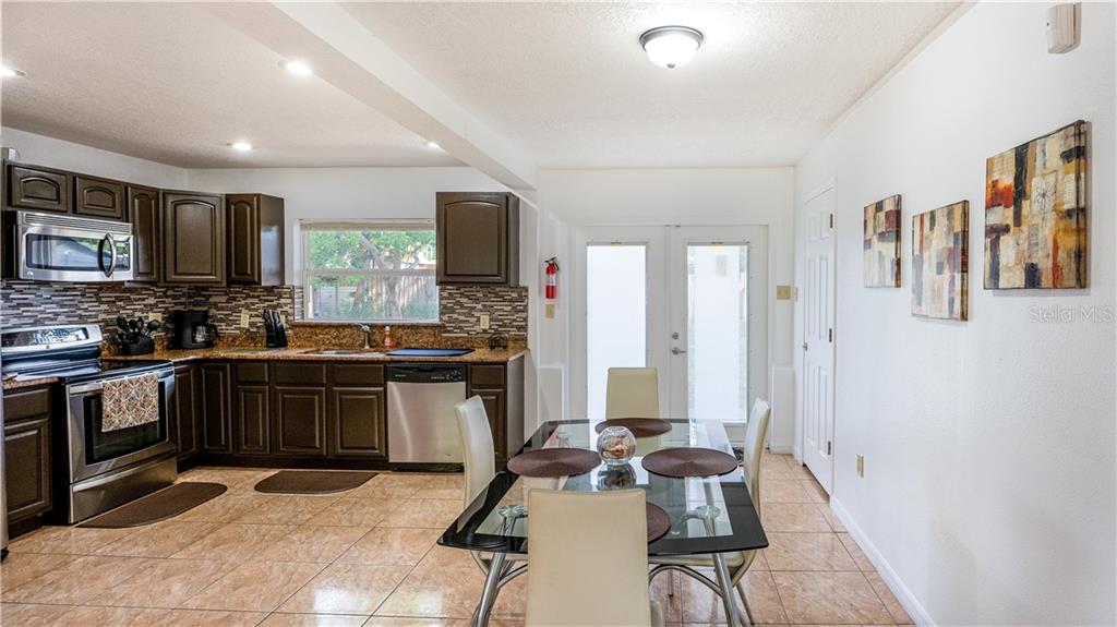 A kitchen and dining area with dark cabinets, stainless steel appliances, and tile flooring — 2721 RAEFORD ROAD, ORLANDO, FL