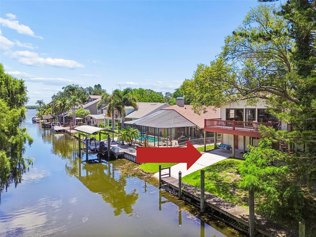 An aerial view of a waterfront house with a deck, boat dock, and concrete patio — 3141 N CANAL DRIVE, PALM HARBOR, FL