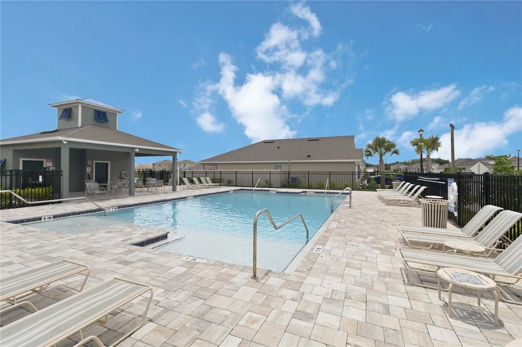 A swimming pool with lounge chairs on a paved deck next to a clubhouse building — 3198 EASTGROVE TERRACE, SANFORD, FL