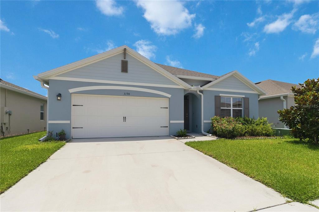 A light blue single-story house features a two-car garage and a front-facing window — 3198 EASTGROVE TERRACE, SANFORD, FL